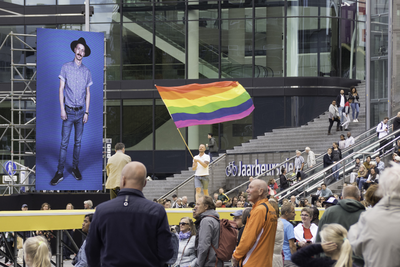 844951 Afbeelding van een man met een regenboogvlag, deelnemer aan 'What Is the City but the People?' (een levend ...